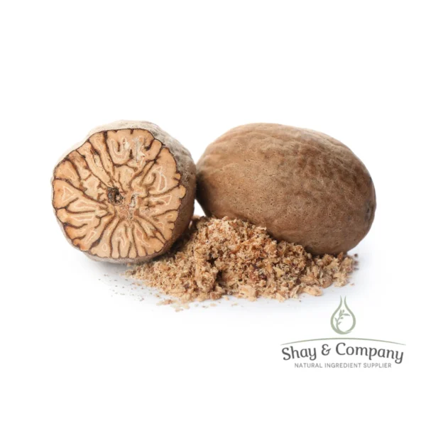 Two nutmeg nuts on a white background with ground nutmeg between them.