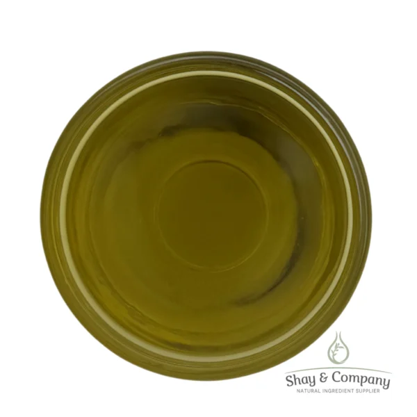 Top-down view of golden-green olive oil in a clear glass dish on white background.