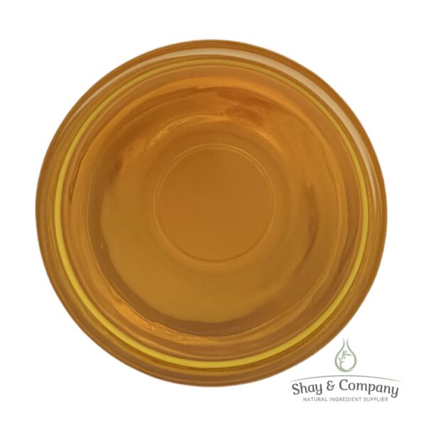 Golden yellow oil or liquid in a circular bowl viewed from above, branded with Shay & Company natural ingredient supplier logo.